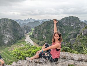 Marta Margullo posando sentada en un muro de piedra y mostrando un paisaje de arrozales típicos de Vietnam a sus espaldas.