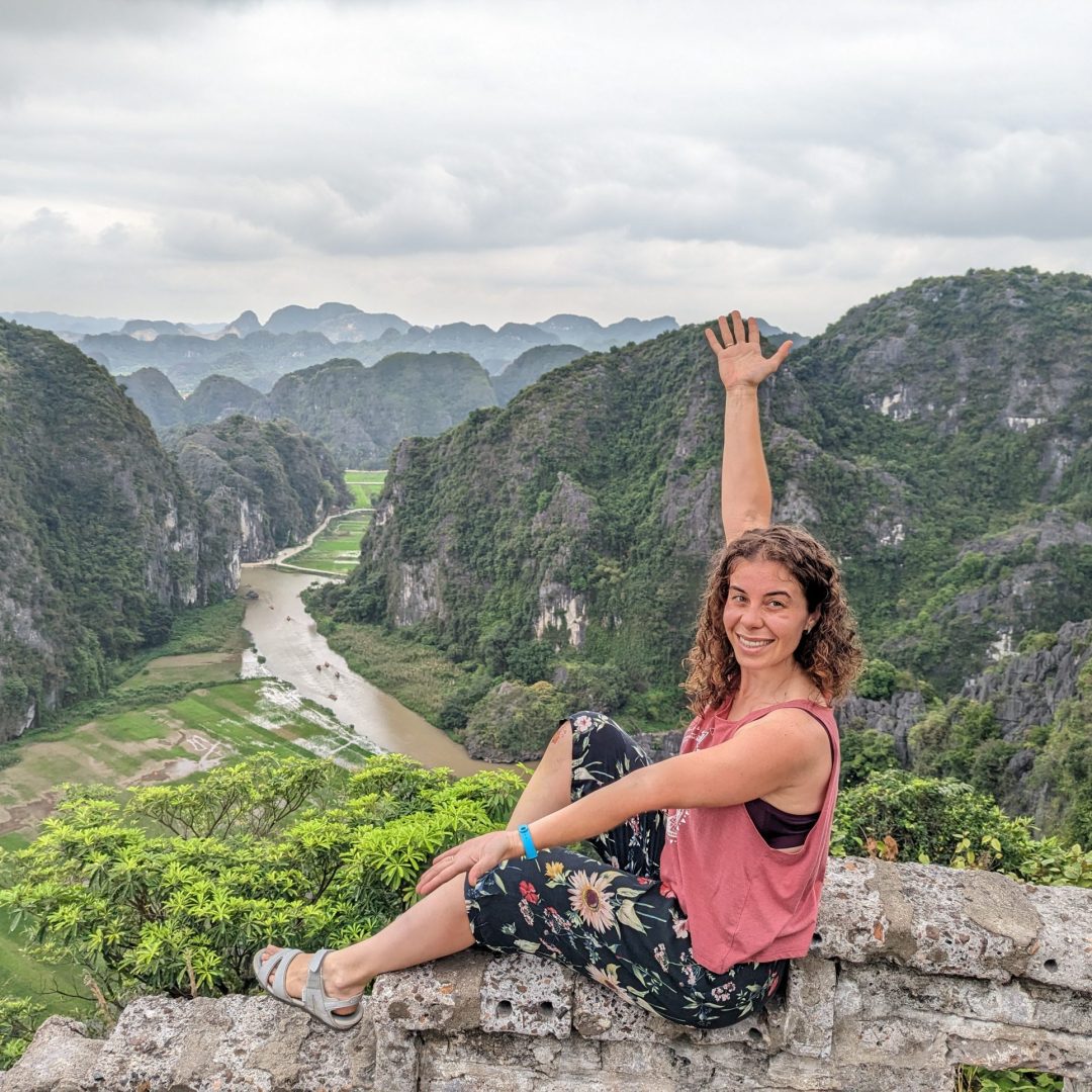 Marta Margullo posando sentada en un muro de piedra y mostrando un paisaje de arrozales típicos de Vietnam a sus espaldas.