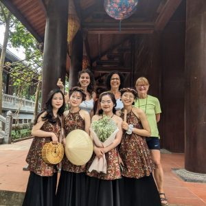 Tres turistas posando con cuatro mujeres jóvenes vietnamitas vestidas con el traje típico.