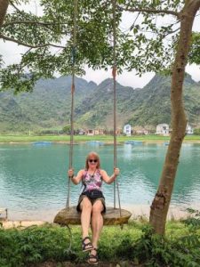 Turista con gafas de sol sentada en un columpio frente a un río en Vietnam